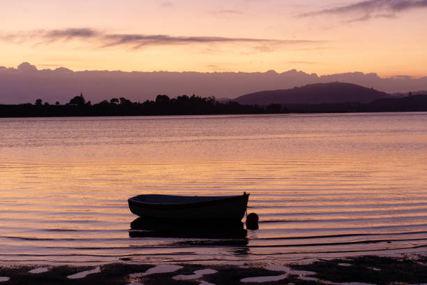 istock One dinghy in silhouette moored in bay with surface ripples at sunrise 1469630483