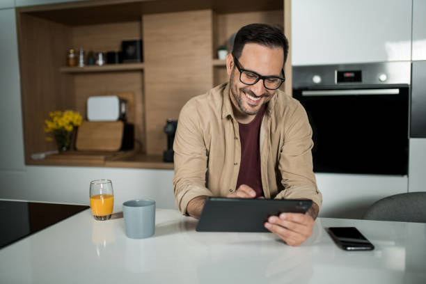 istock Happy young man using digital tablet on kitchen counter at home. 1469634565