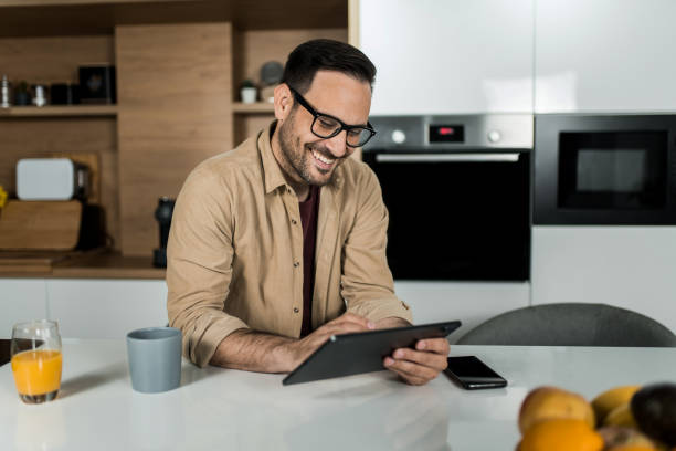 istock Happy young man using digital tablet on kitchen counter at home. 1469634594