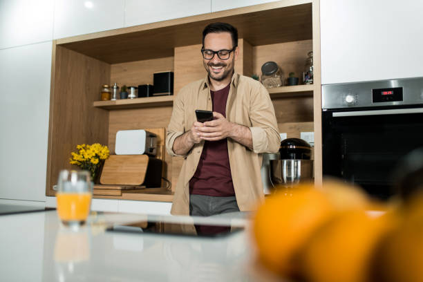 istock Happy young man using his cell phone in the kitchen at home. 1469634604