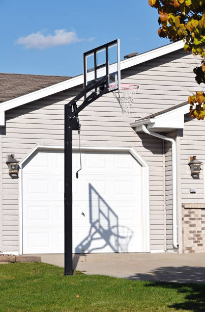 Basketball goal and its shadow on the garage.