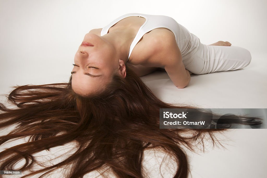 Woman in lotus fish Yoga posture (Halasana) Young lady practicing yoga in lotus fish posture (Matsyasana) in white clothes with red hair spread out on white background, high-key image. Stretching Stock Photo