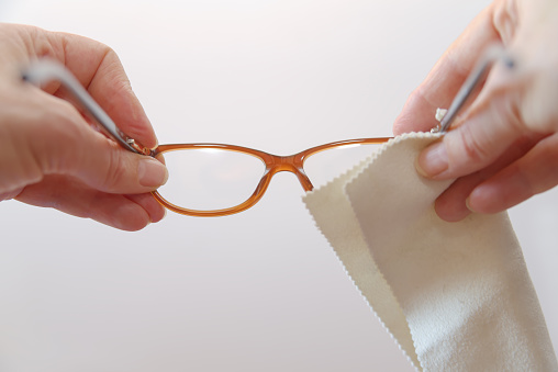 Woman cleaning foggy glasses with a cloth