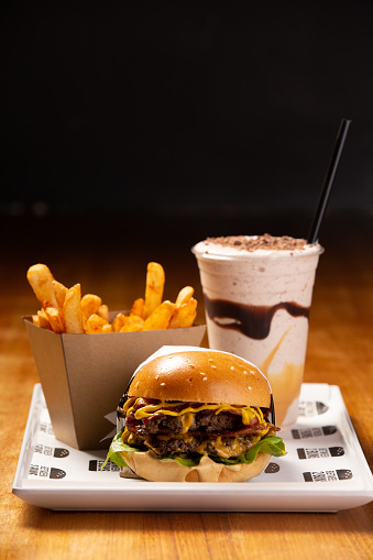 A hamburger, fries and thick shake are seen served at a burger bar.