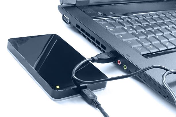 An external hard drive plugged into a laptop An external hard drive plugged into a laptop computer via an USB cable external hard disk drive stock pictures, royalty-free photos & images