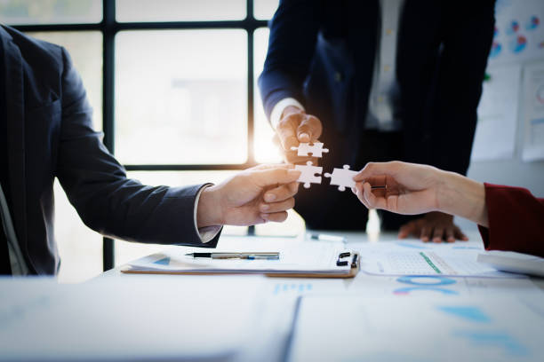Business people with jigsaw puzzle pieces in office, Successful teamwork and partnership concept.