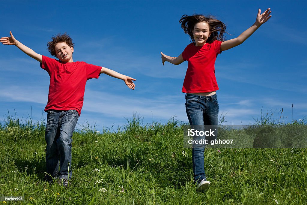 Niños correr, saltar al aire libre frente a cielo azul - Foto de stock de 12-13 años libre de derechos