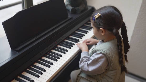 little girl playing the piano little girl playing the piano girl playing piano stock pictures, royalty-free photos & images