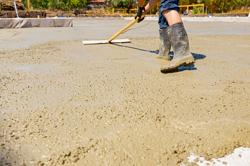 Construction worker, mason is leveling fresh concrete using handmade tool
