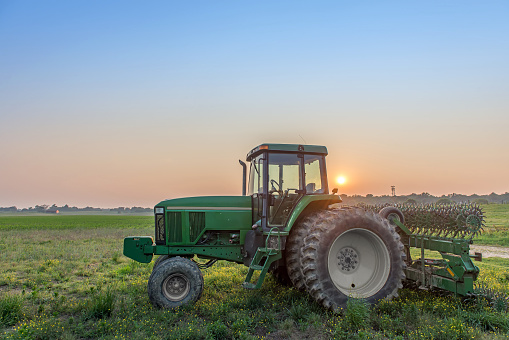 Agricultural landscape of a tractor in a field on a Maryland farm with the sun setting.