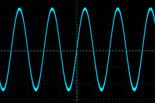 Photograph of a blue sine wave on a grapgical oscilloscope display.