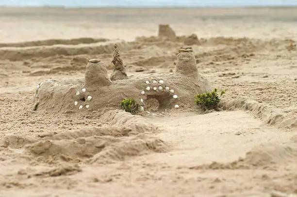 Photo of Lovely sandcastle with few towers and road, decorated by seashells