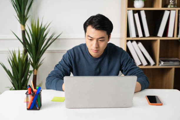 istock image of Asian man sitting at home working 1469656055