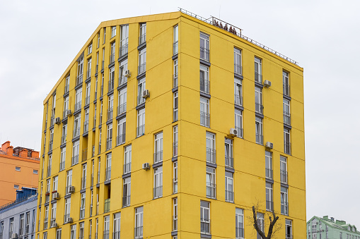 Fragment of the yellow facades of the modern multistory apartment building against the cloudy sky