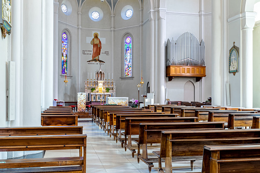 Alba, Italy - July 23, 2020: View of pews, altar and organ inside of Divin Maestro - a roman catholic parish church recently renovated, located in small town of Alba in Piedmont, Northern Italy.