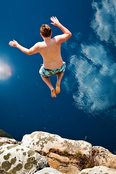 istock Boy Jumping Off Cliff Into Blue Water 146966118