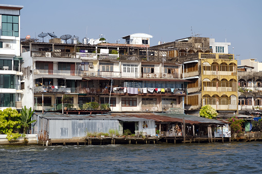 Old residential buildings on the Chao Phraya river waterfront, Bangkok, Thailand.