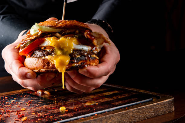 istock Man's hands holding burger with meat, cheese and vegetables 1469664576