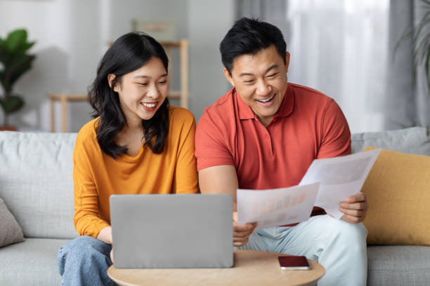 istock Happy asian spouses paying bills online, using laptop 1469667763