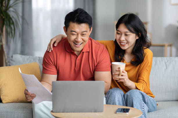 istock Smiling asian spouses paying bills online, using laptop 1469667779