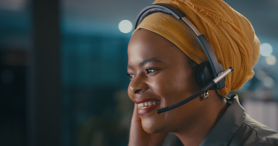 Customer service of happy black woman in call center at night for contact, sales consulting or telecom. Telemarketing worker, female consultant and dark office for IT support, questions and solution