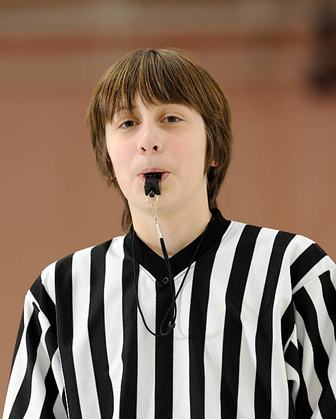 Teenage caucasian boy referees a basketball game