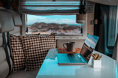 Alternative office for smart working and digital nomad vanlife lifestyle. One laptop on the camper van table with nature beach amazing beautiful view. Freedom lifestyle people. Online work business