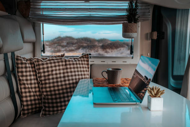 Alternative office for smart working and digital nomad vanlife lifestyle. One laptop on the camper van table with nature beach amazing beautiful view. Freedom lifestyle people. Online work business stock photo