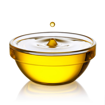 cooking oil with flying drop in glass bowl isolated on white background