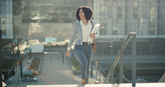 Black woman in city, folder and travel to work with corporate lawyer, business and commute, walking outdoor with legal employee. Attorney in Chicago, freedom and cityscape with professional person