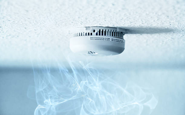 Smoke detector A smoke detector installed at a ceiling with smoke. Small depth of field. smoke detector photos stock pictures, royalty-free photos & images