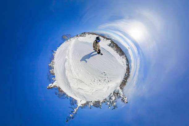 An abstract like above view of what looks like a tiny snow planet with one man snowboarding seen from high above.