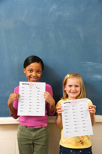 Students in Classroom Young students holding spelling tests with good grades. Vertically framed shot. good grades stock pictures, royalty-free photos & images