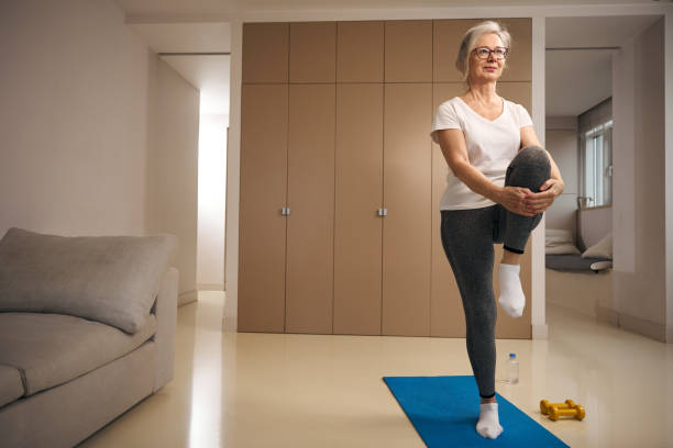 istock Elderly woman stands on one leg in a tree pose 1469684532