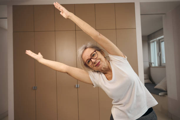 istock Cute grandmother is standing in a room in triangle pose 1469684541