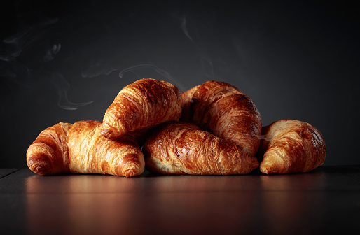 Freshly baked croissants on a black ceramic table. Traditional French kitchen. Copy space.