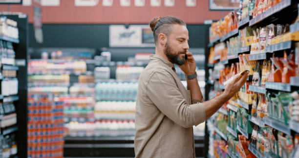 rozmowa telefoniczna, zakupy i zakupy spożywcze z mężczyzną w supermarkecie na jedzenie, wybór i opcję rabatową na półce. zdrowie, komunikacja i sprzedaż z klientem w sklepie w celu zakupu detalicznego, produktu i konsumenta - store on the phone supermarket sale zdjęcia i obrazy z banku zdjęć