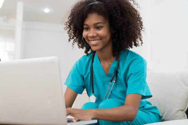 happy young nurse working with laptop computer in the hospital. smiling young female doctor or young nurse giving advices to the patients online by laptop computer at home - medical assistant imagens e fotografias de stock