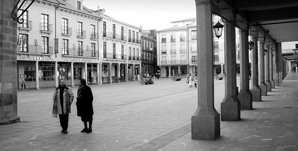 Astorga, Spain - february, 3, 2010 : main townsquare in Astorga, León, Spain, seen from under the arcade that surrounds it. Winter afternoon, two senior women walking and talking .