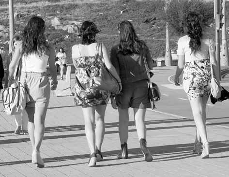 A Coruña, Spain_ July 17 2010: Rear view of four beautiful young women walking along avenue sidewalk, A Coruña, Galicia, Spain.