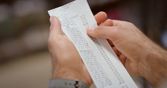 Cash register, receipt and man customer holding financial payment bill for price and cost check. Bookkeeping paper, banking balance and retail shopping information of shop debt after buying product