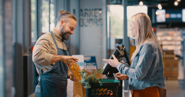 épicerie, paiement du marché alimentaire et client avec employé du supermarché à la caisse. rabais au détail, caisse enregistreuse et promotion de produits avec une femme au comptoir d’un magasin qui paie l’épicerie - checkout counter cash register retail supermarket photos et images de collection