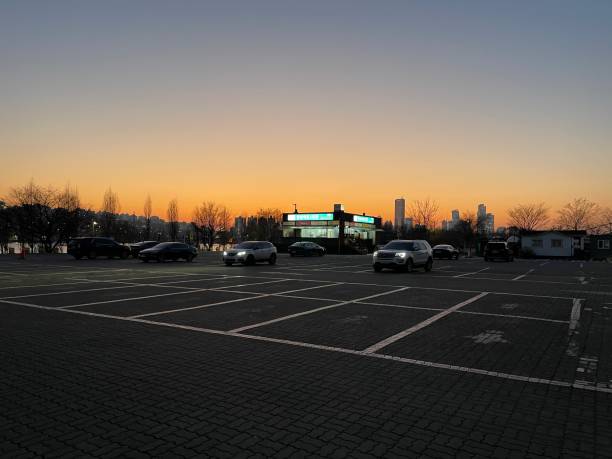 An empty parking lot under a cloudscape at sunset.