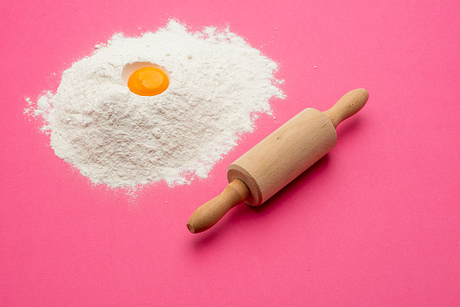 High angle view Studio shot; eggs, flour and rolling pin on a pink background.
