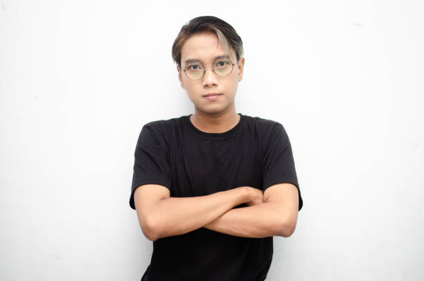 An Asian man with peek a boo colored hair who is thoughtful and perplexed decides what to choose as it is displayed against a white background. The man is unsure and uncertain.