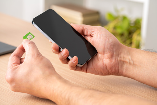 Close up of a man hands putting the sim card on the phone on a table