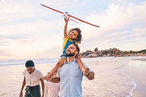 Family, walking or airplane fun on sunset beach, ocean or sea in freedom holiday, energy bonding or playing game. Smile, happy or children with flying toys, piggyback or interracial parents by water