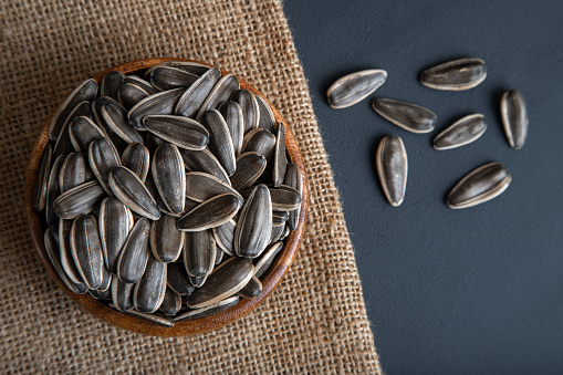 Black sunflower seeds in a bowl on dark background