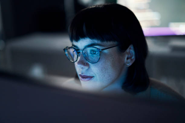 Concentrating, neon and night with woman and computer for software engineering, developer and designer. Cyber security, data science and code with employee in office for coding, website or technology stock photo