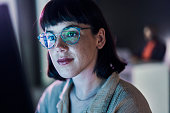 Business woman face, computer and ux coding of young employee with blue light and glasses. Digital code, hacker ai and reading of a female worker at night planning with online cybersecurity data